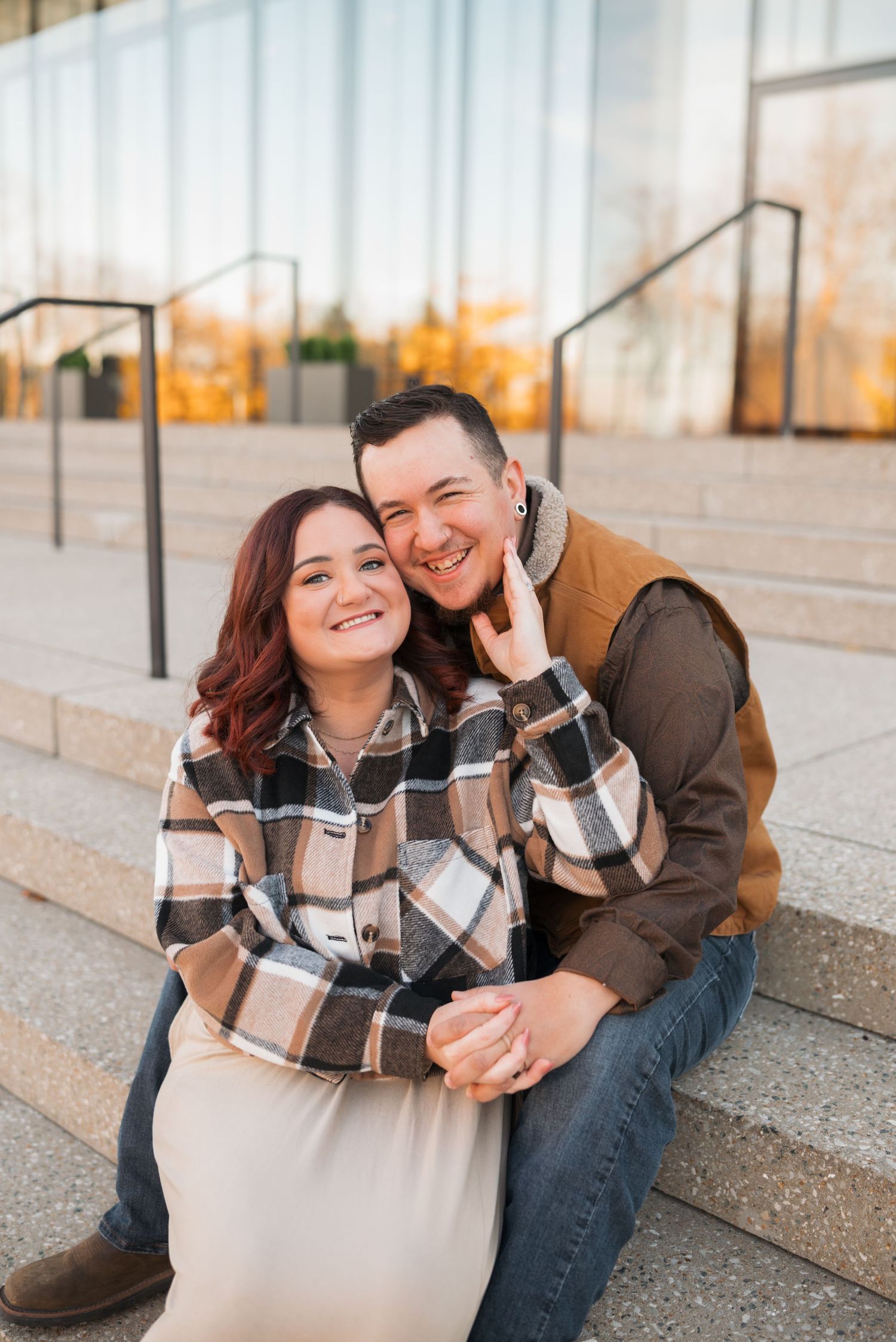 A couple shares a playful moment while sitting on concrete steps.