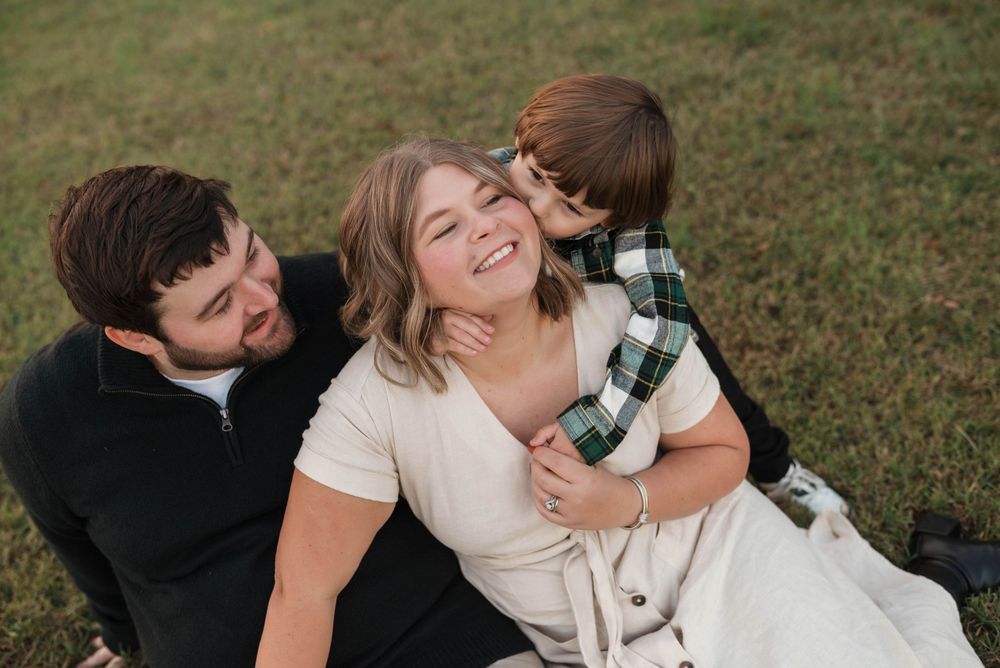 Romantic couple shares tender moments in a grassy field during an outdoor photo session.
