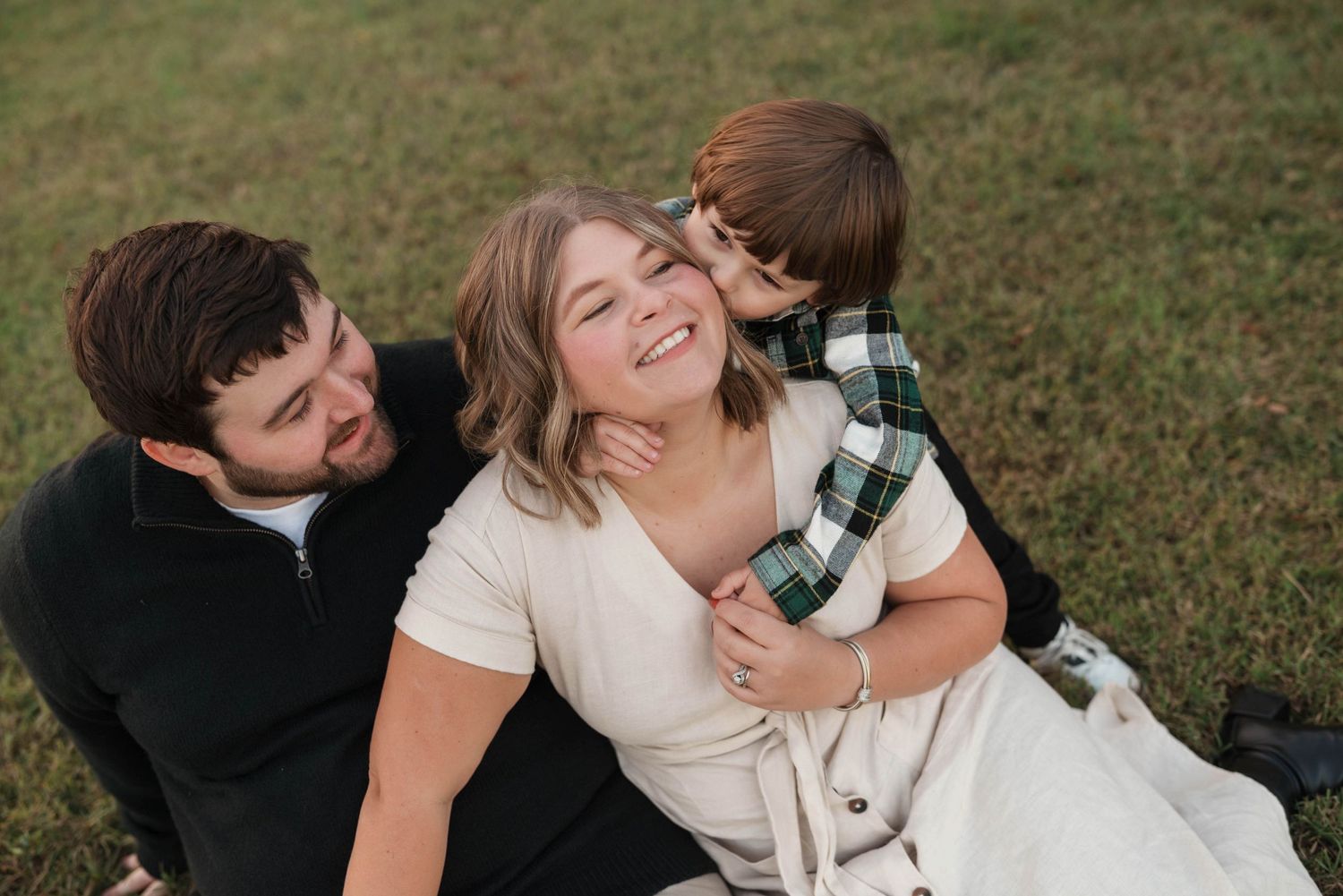 Romantic couple shares tender moments in a grassy field during an outdoor photo session.