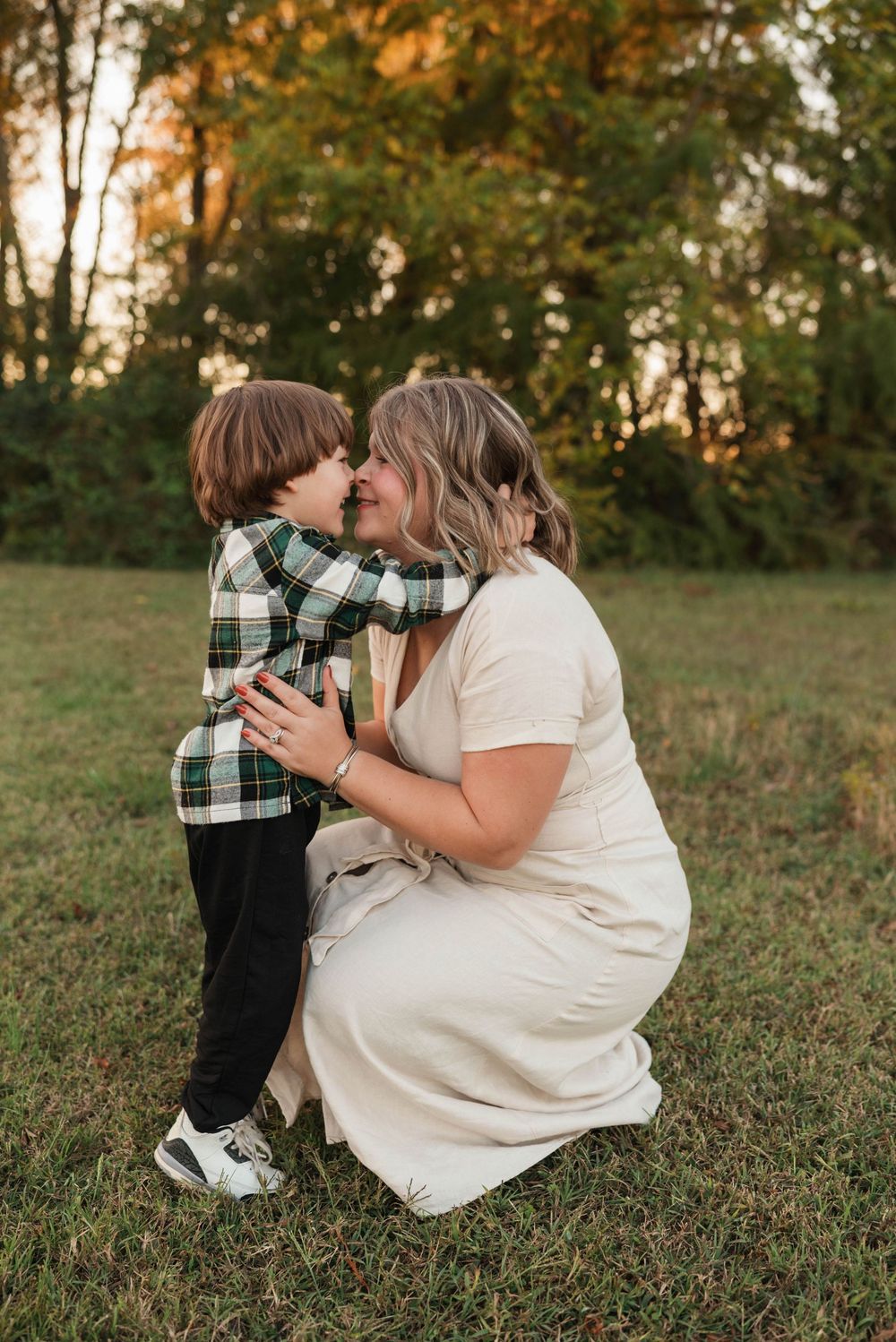 A tender moment shared between parent and child sitting together on grassy hill at sunset.