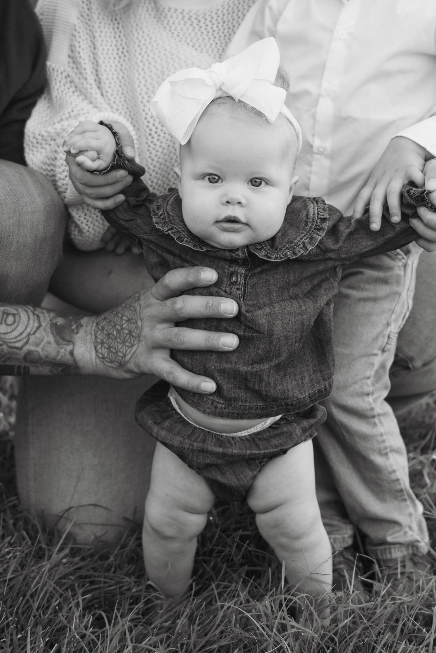 A series of black and white photos showing a baby's legs in denim overalls being supported by adult hands.