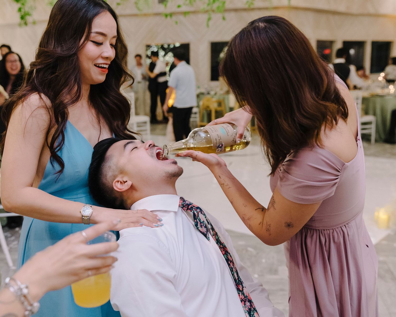 Wedding guests enthusiastically dance together in formal attire at an indoor reception venue.