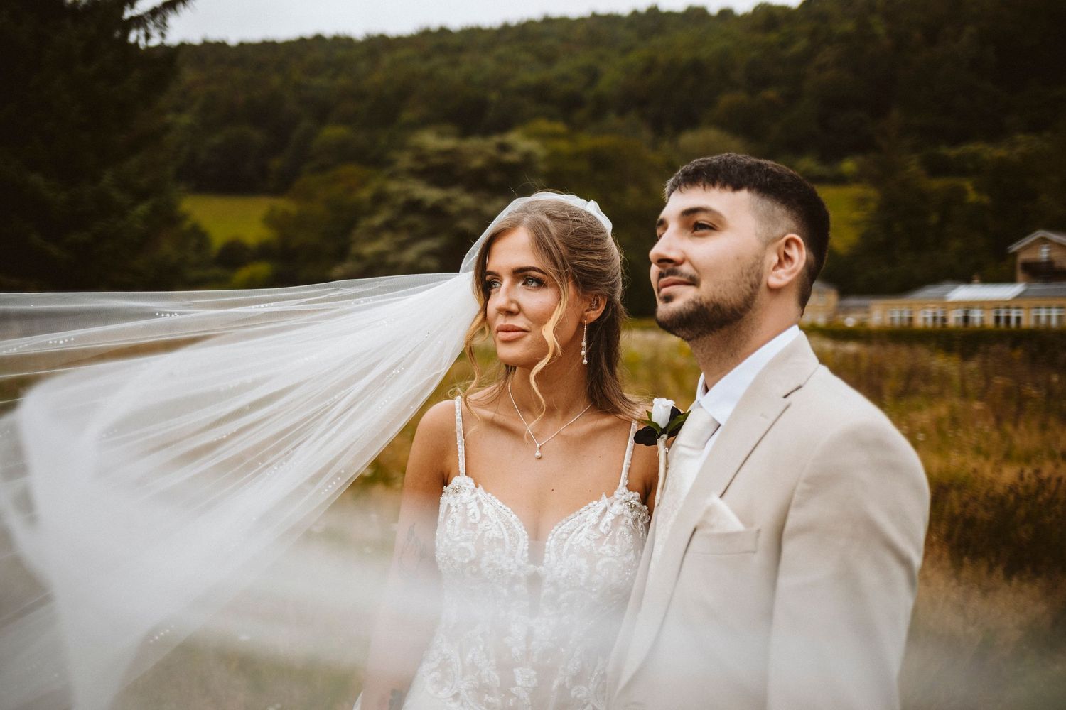 A romantic outdoor wedding photoshoot in a scenic field with mountains and golden light at sunset.