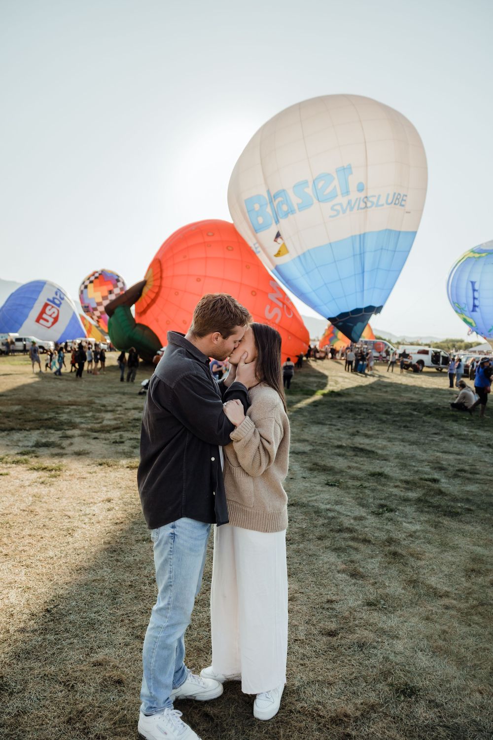Couple sharing a kiss at hot air balloon festival with large Elaser Swisslube branded balloon behind them.