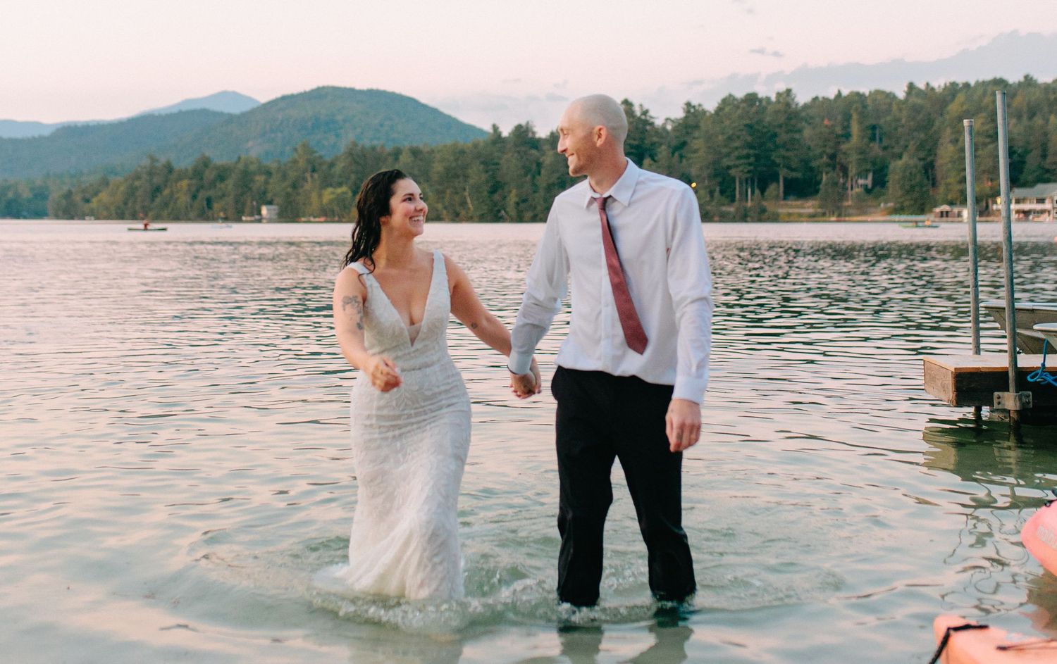 A couple wades in the lake water during a playful sunset wedding photo session.