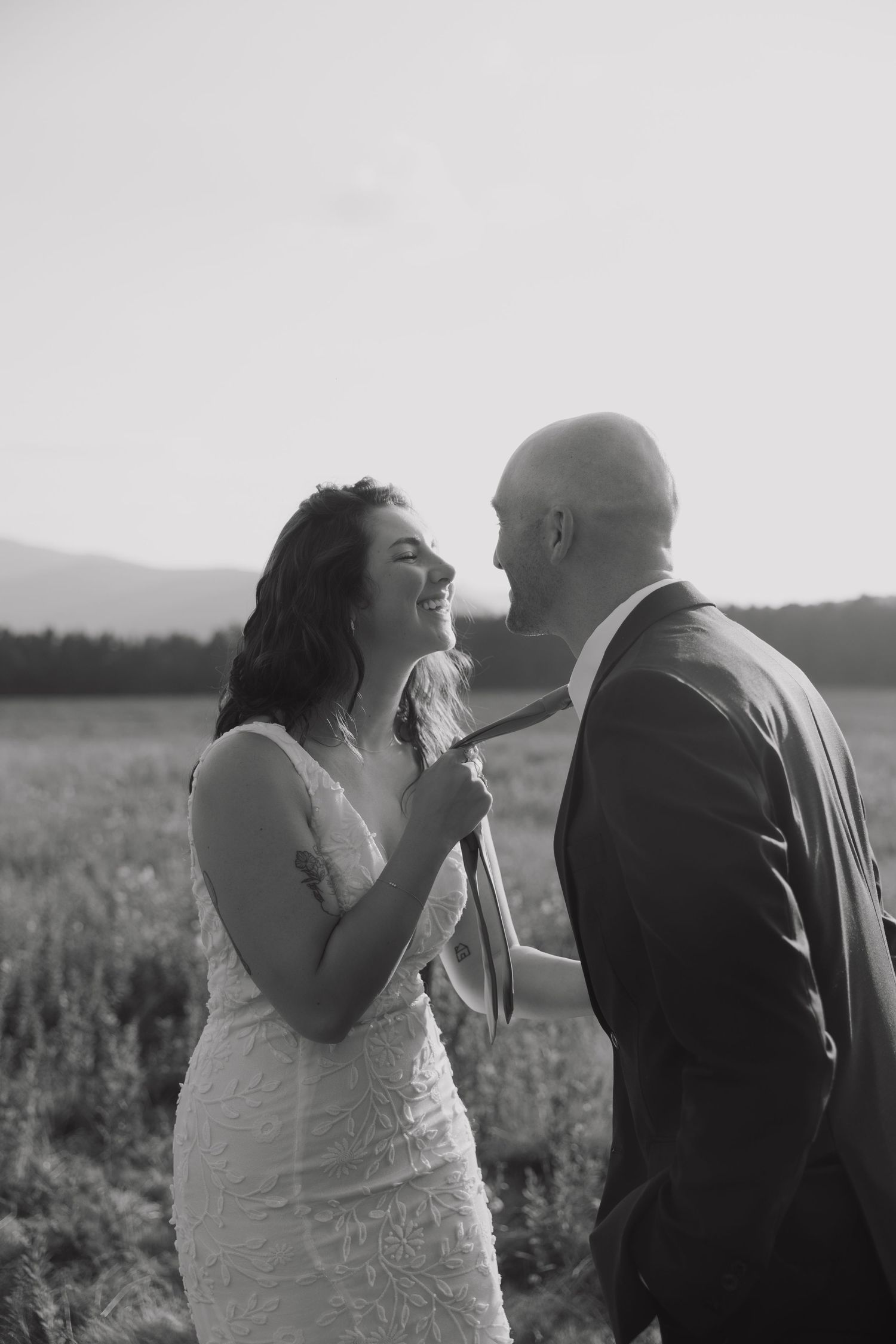 A romantic series of black and white photos showing a couple sharing tender moments in a field at sunset.