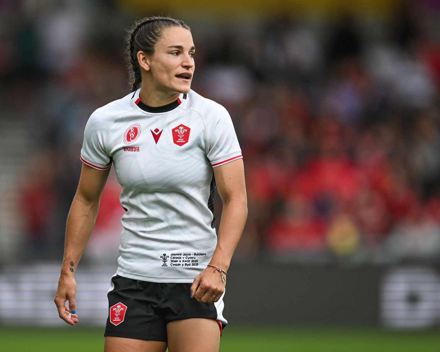 Rugby athlete in white jersey runs across field during competitive match action.