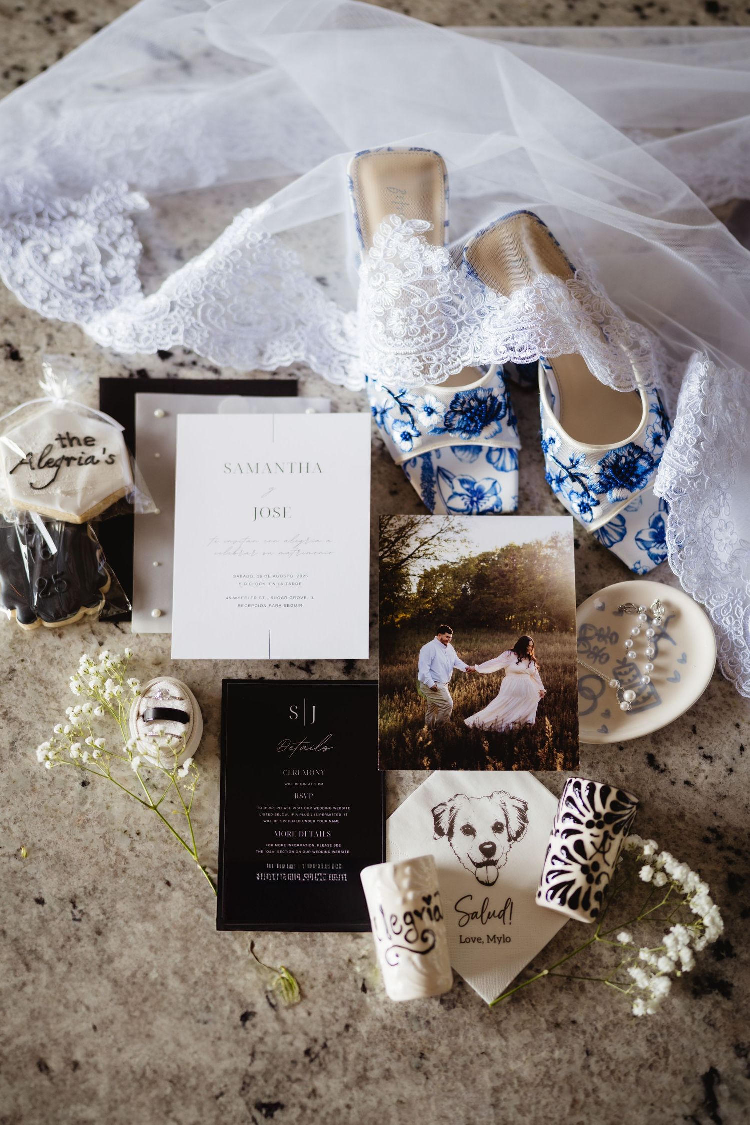 Elegant black and white wedding invitation suite and accessories photographed artistically on textured stone surface.