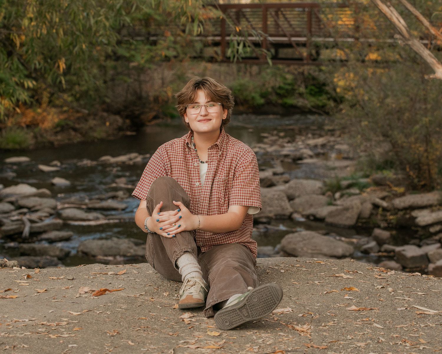 Senior girl posing in front of a mountain creek for her fall senior portrait session.