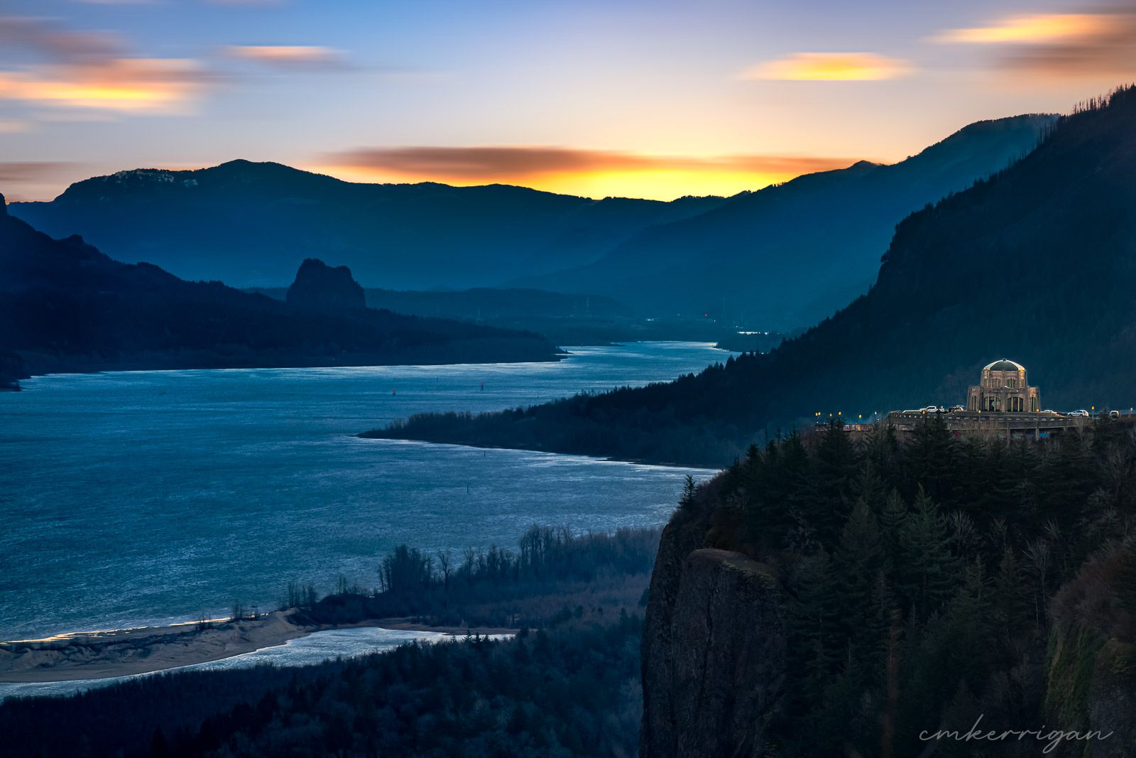 Vibrant sunset over the Columbia River Gorge with silhouetted mountains and dramatic clouds.