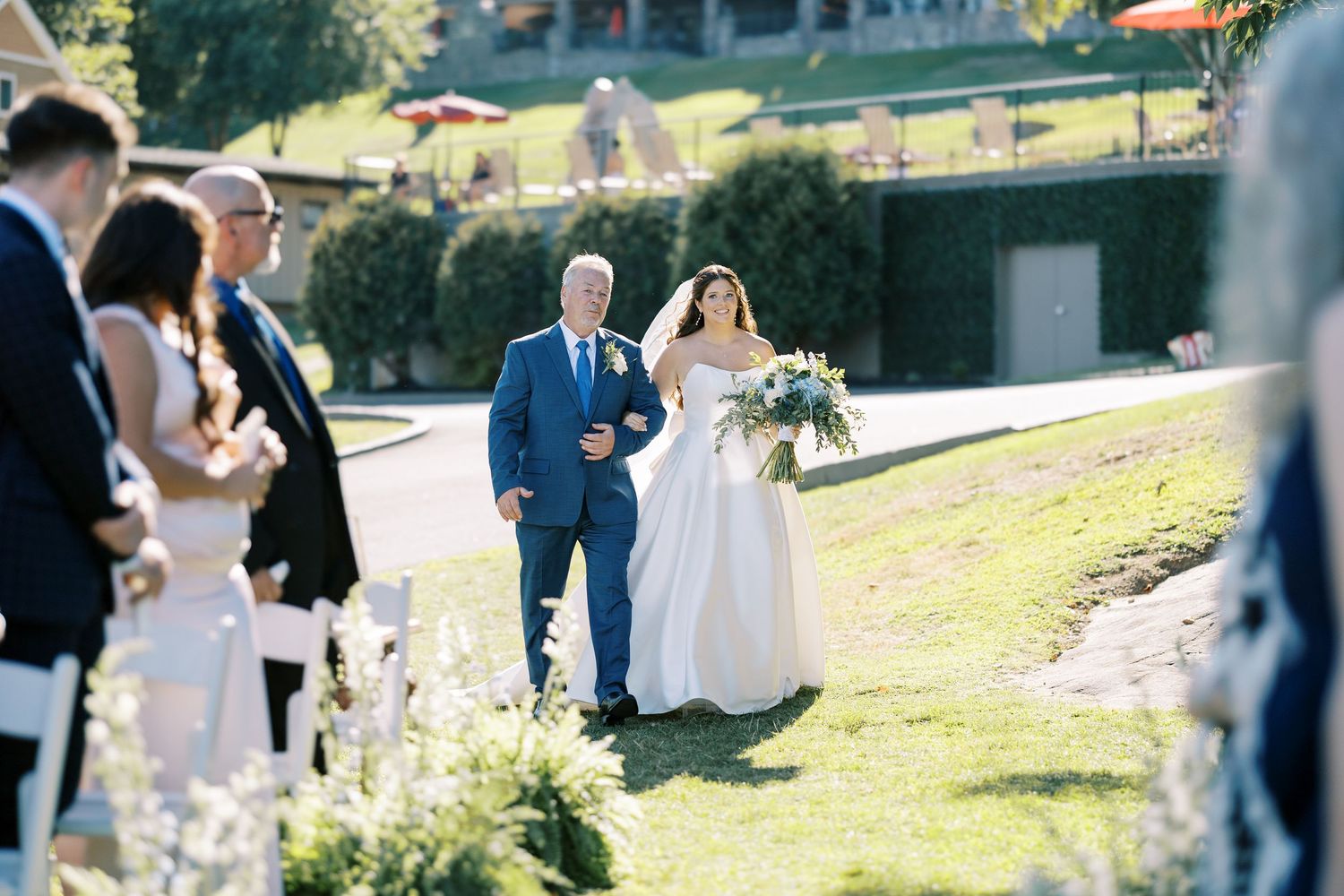 A set of outdoor wedding ceremony photos showing guests gathered on a lakeside dock with mountains in the background.