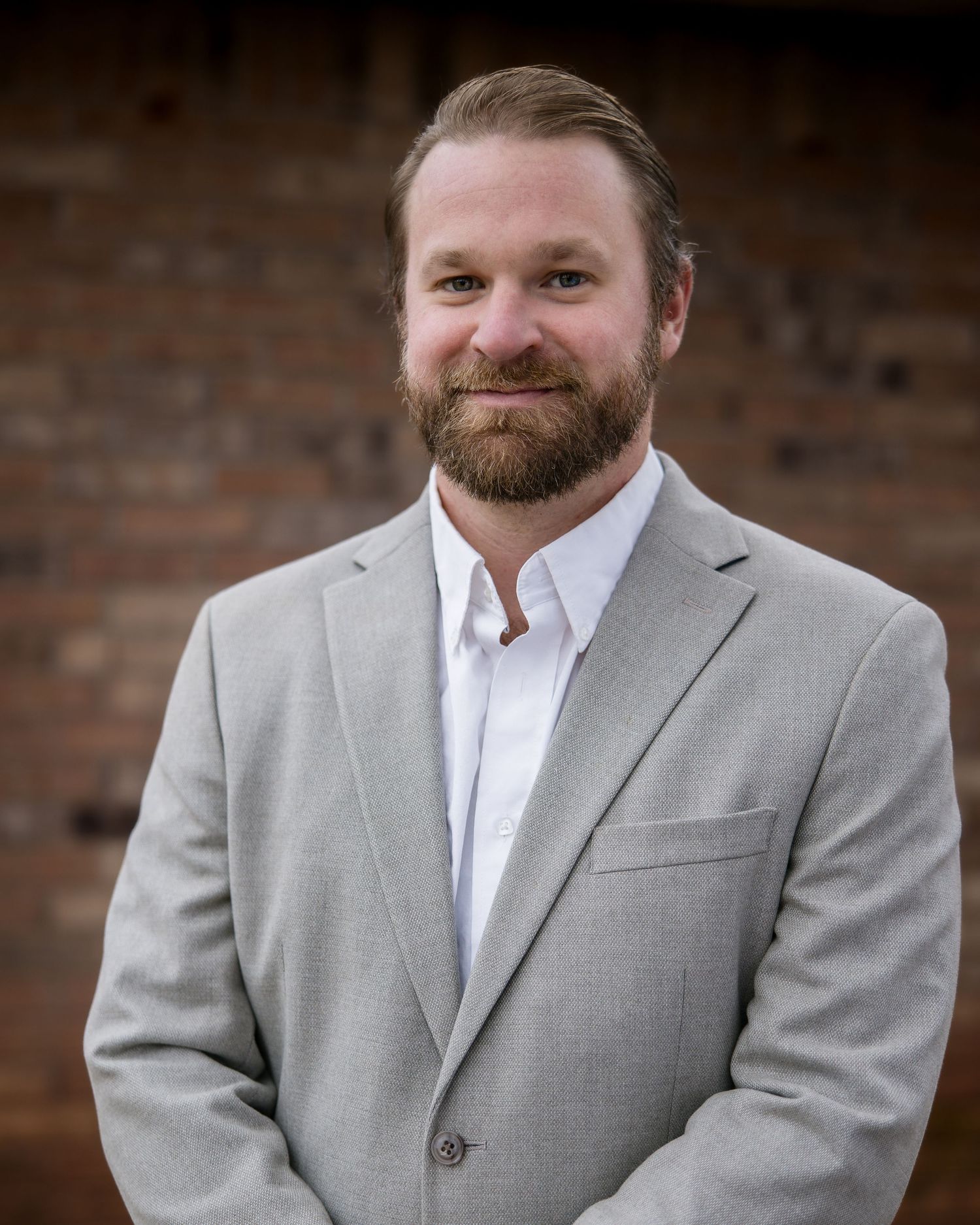 Professional portrait series showing person in gray suit and white shirt against rustic brick backdrop.