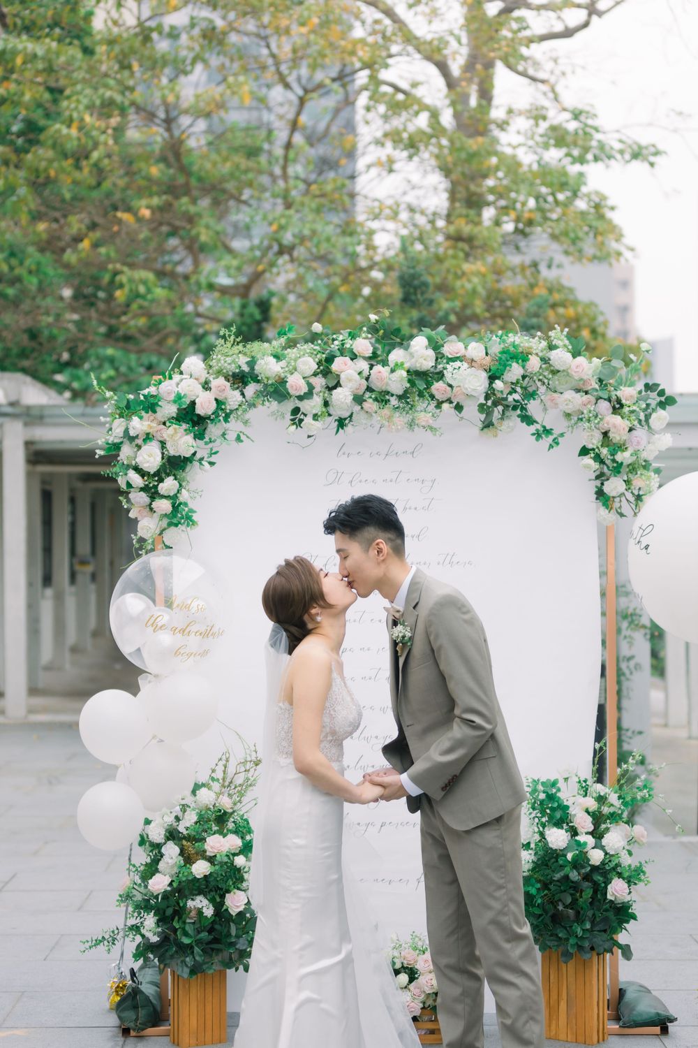 A romantic wedding ceremony sequence with a white balloon arch and green floral decorations against an outdoor backdrop.