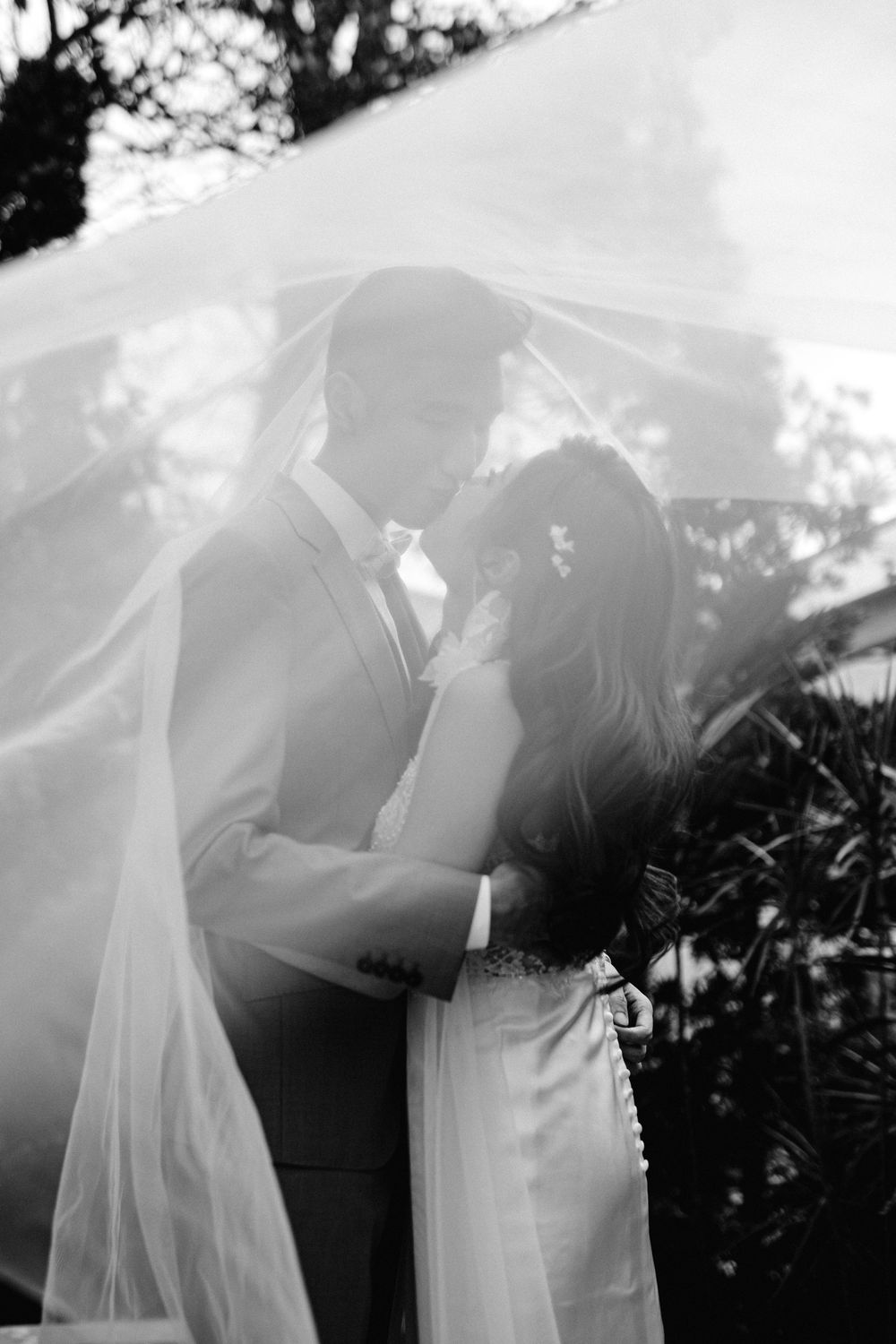 A romantic black and white photo sequence shows a couple in wedding attire sharing an intimate kiss outdoors.