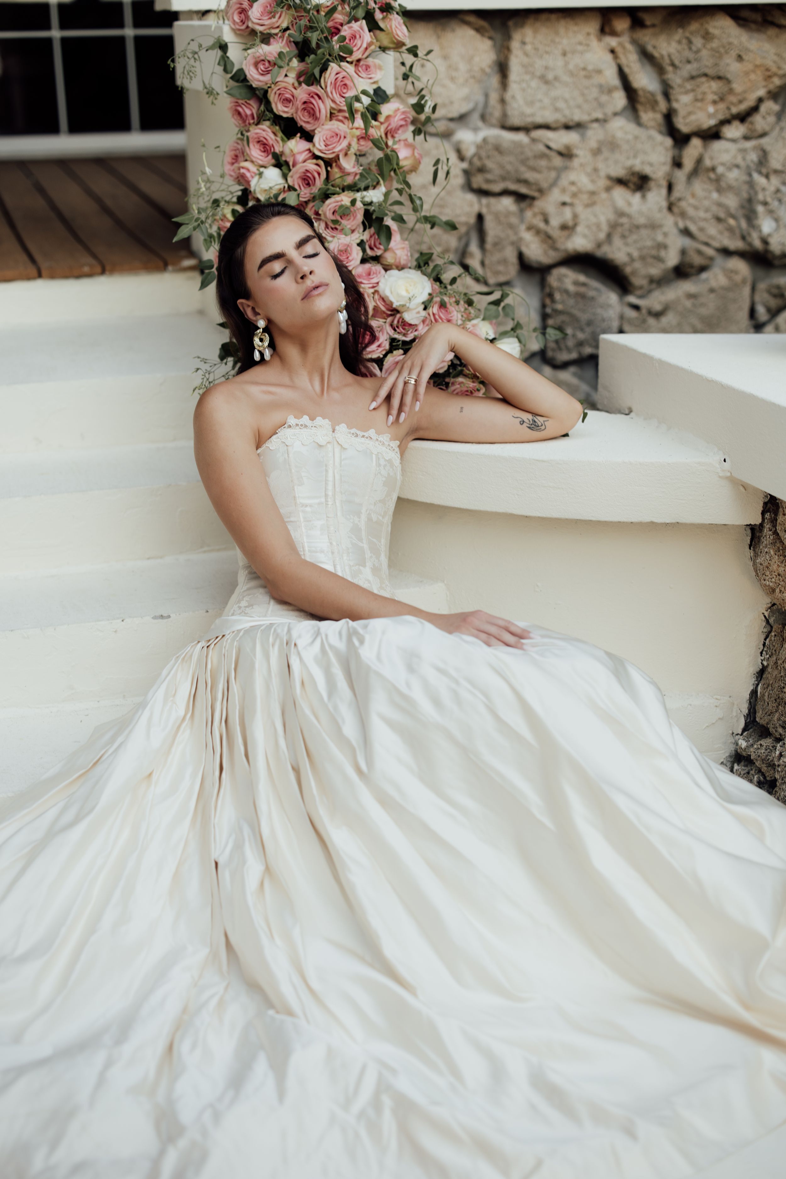 A romantic bridal portrait series featuring a flowing white wedding gown against a rustic stone wall backdrop.