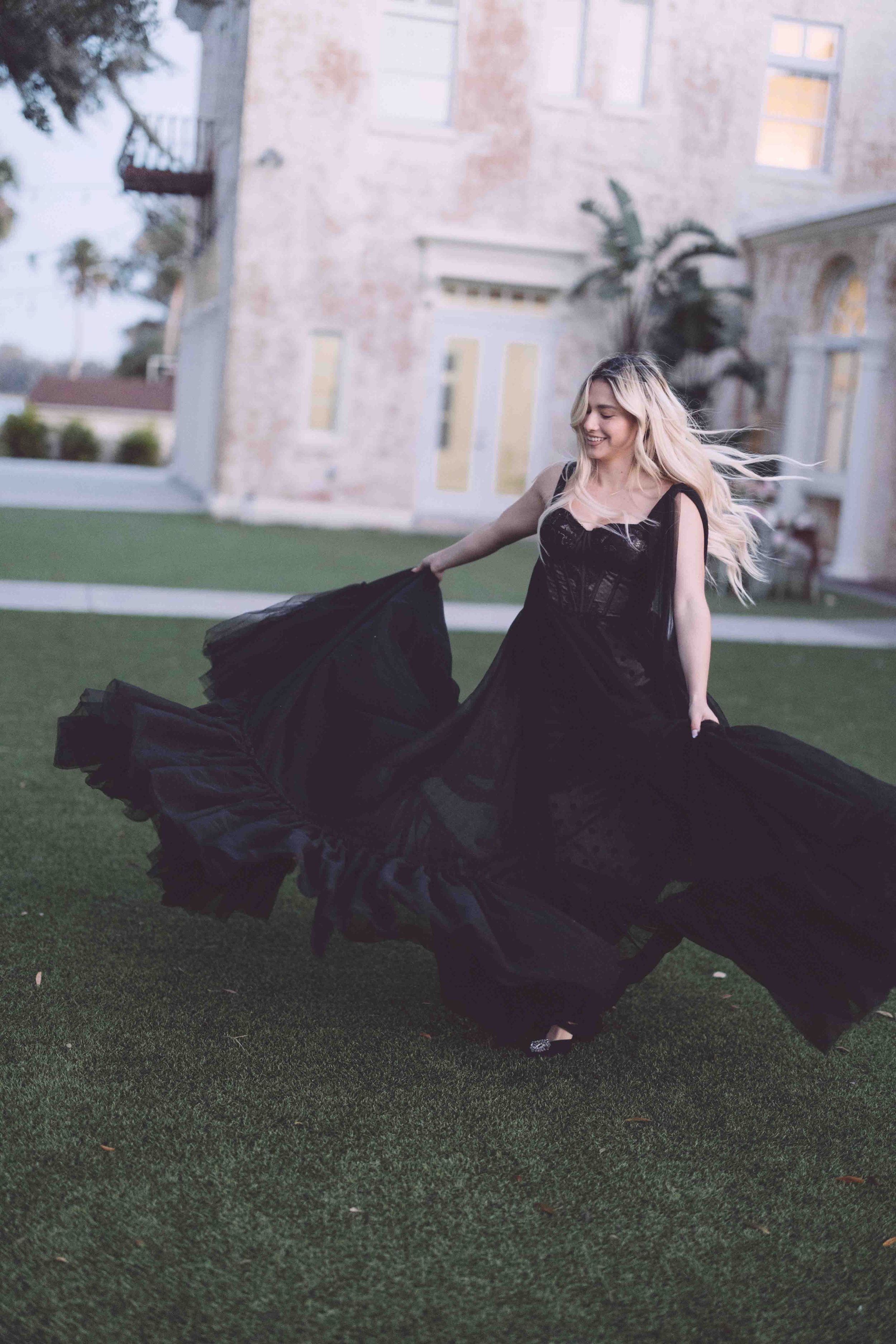 A flowing black gown billows elegantly across a manicured green lawn in a series of dramatic outdoor fashion photographs.