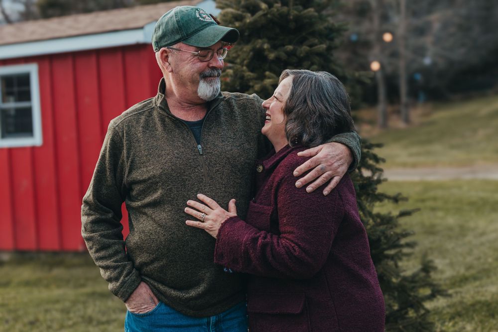 A casual outdoor portrait session showing affectionate moments near a red building.