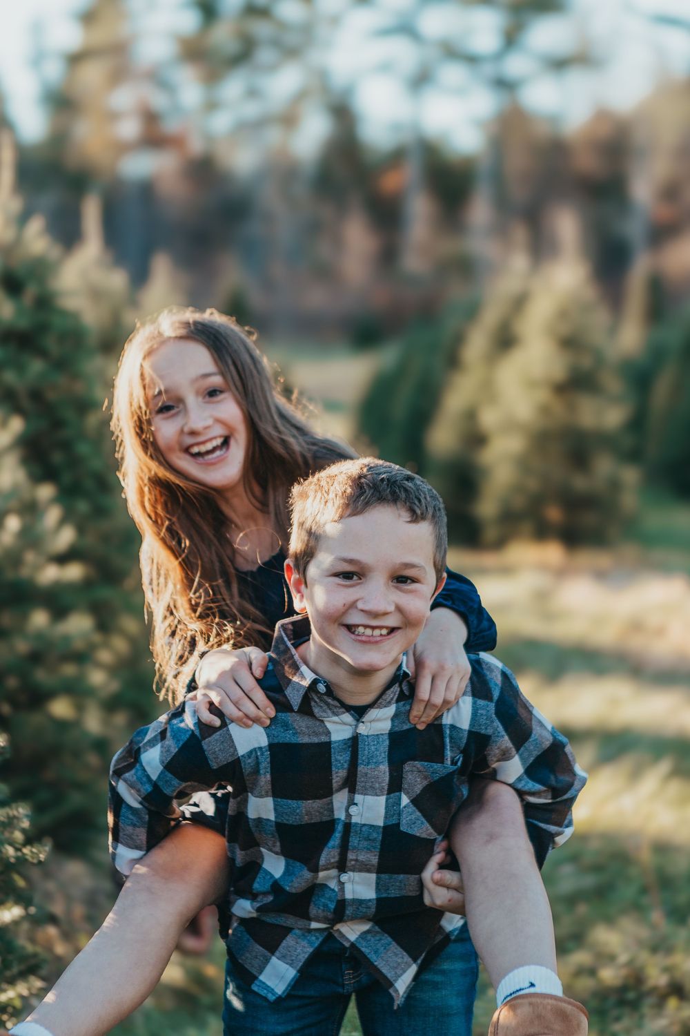 Two people laugh and embrace while wearing coordinating blue plaid shirts in a sunny outdoor setting.