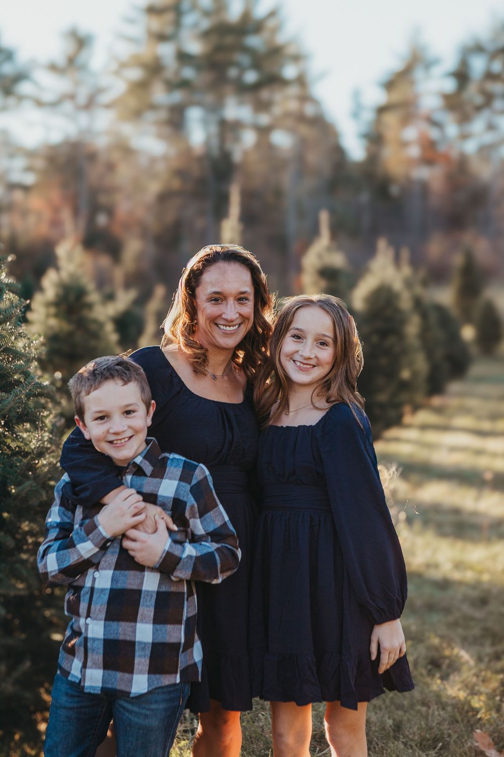 A sunset family portrait with coordinated navy and plaid outfits in a natural setting.