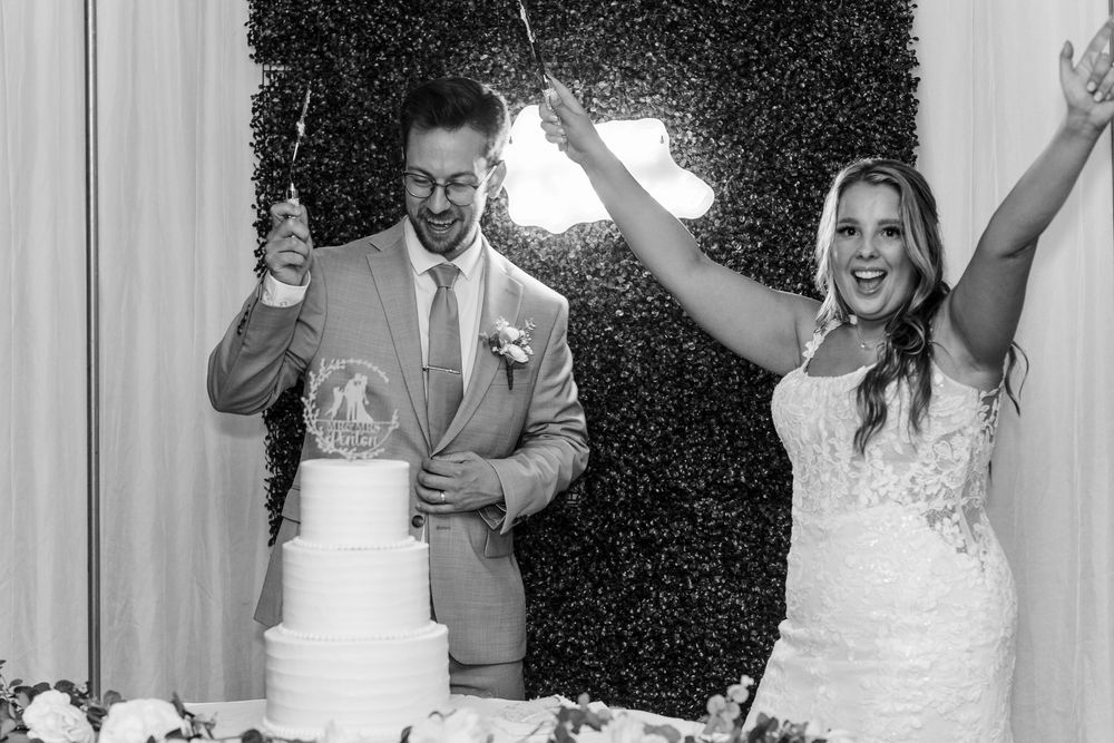 Joyful wedding party gathered together in formal attire, celebrating with arms raised in celebration.