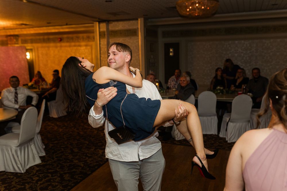 People dancing together at a lively wedding reception with a dimly lit ballroom atmosphere.
