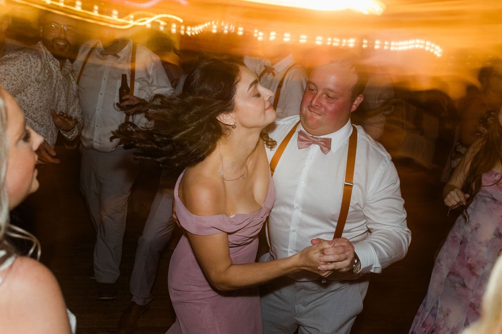 A couple dances together under warm ambient lighting at an evening celebration event.