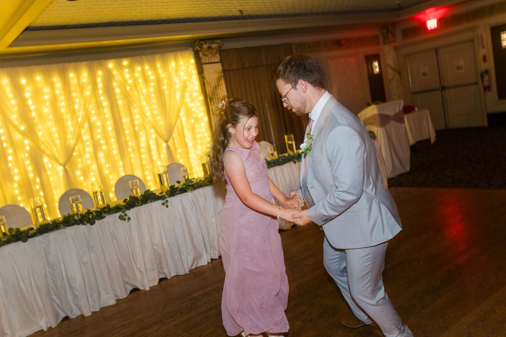 A romantic couple dances together on a glowing dance floor under warm decorative lighting at an evening event.