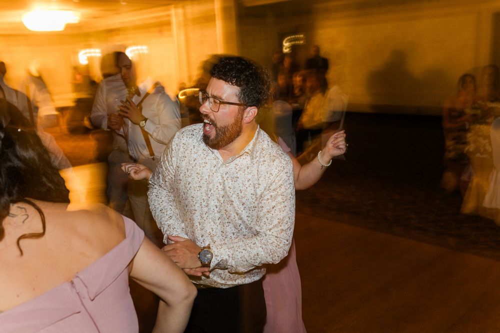 A couple dances energetically together on an amber-lit dance floor during a reception celebration.