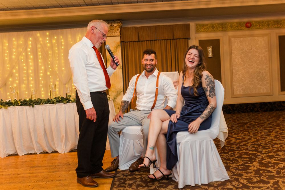 Couples dance together on a carpeted ballroom floor at a wedding reception with string lights illuminating the background.