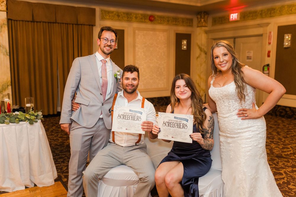 Wedding party poses together in a formal reception venue decorated in elegant neutral tones and gold details.
