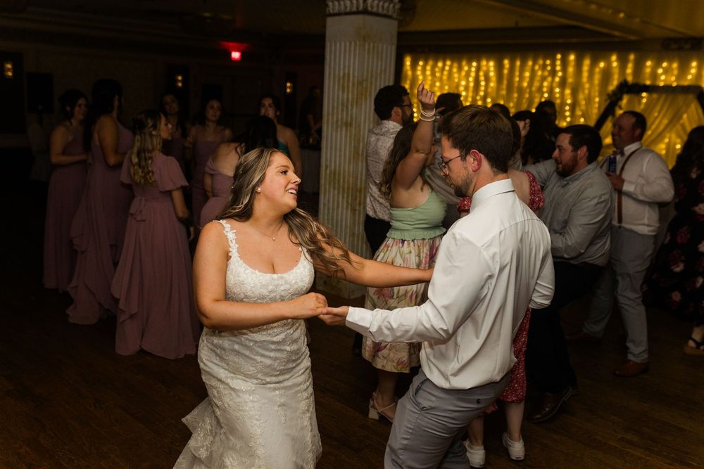 Couples dancing together at a wedding reception with string lights glowing in the background.