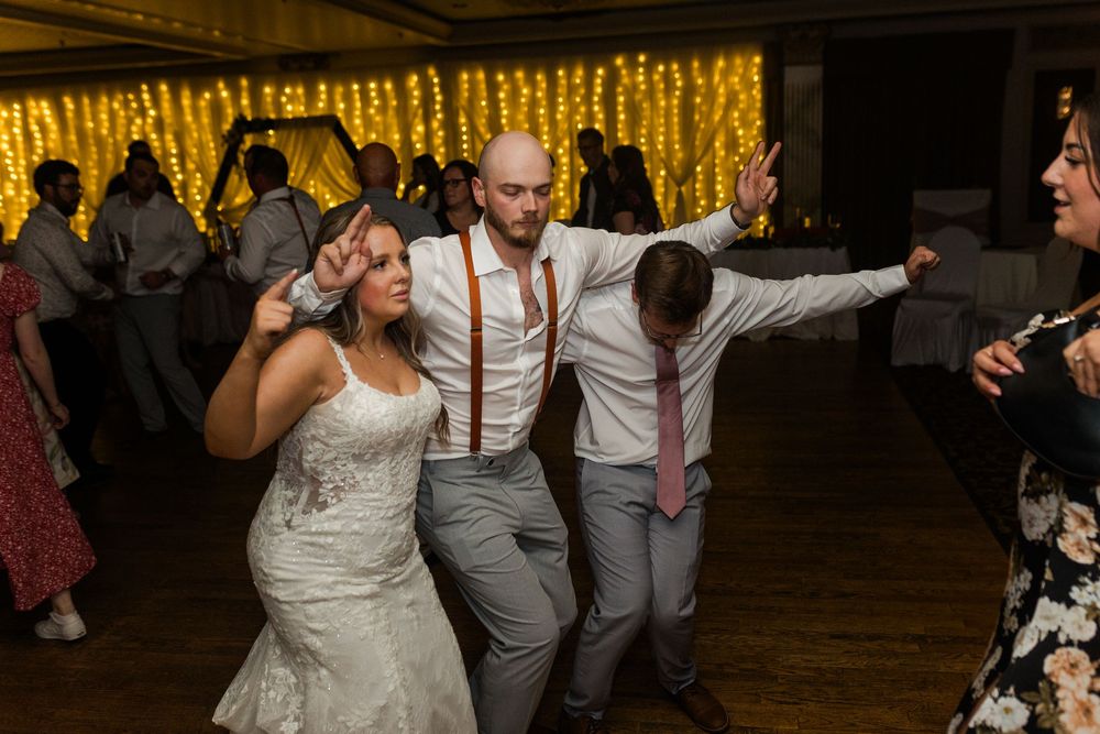 Wedding celebration on a dark wooden dance floor with twinkle lights creating a warm ambiance.