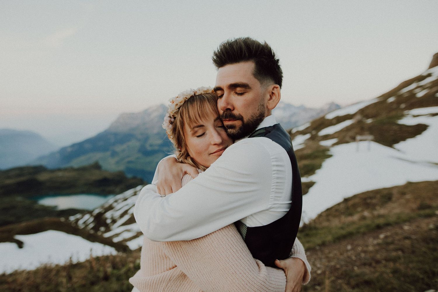 A romantic elopement moment in the Swiss Alps with snow-capped mountains and a lake in the background.