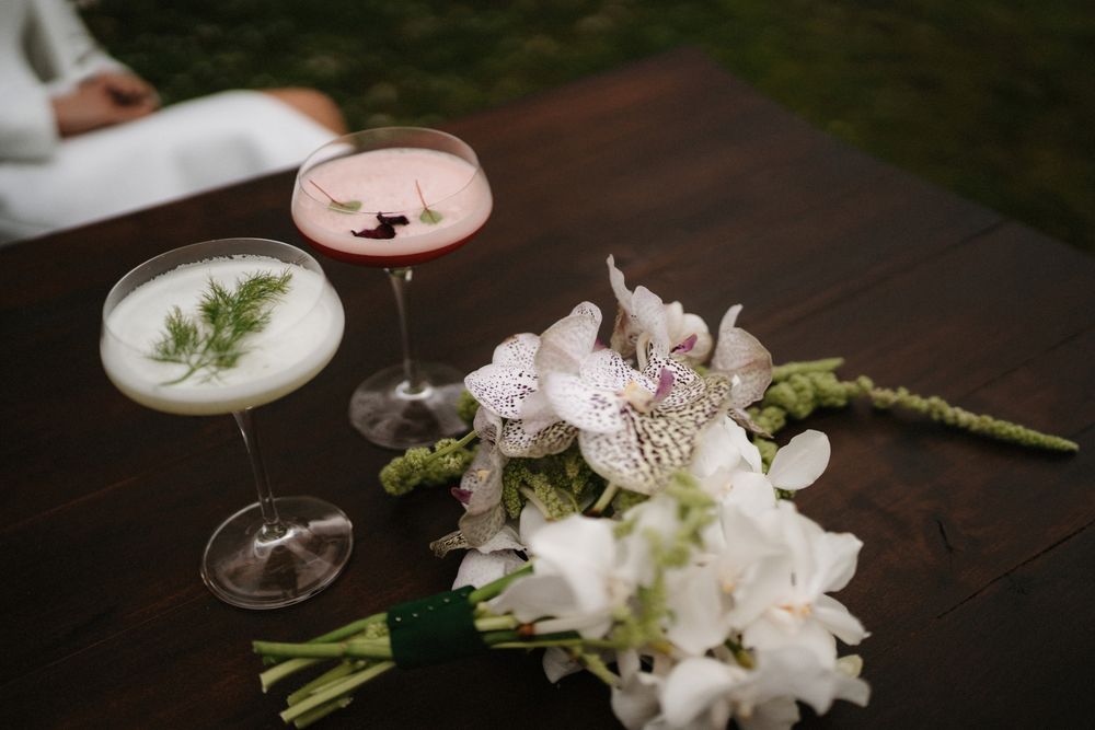 White floral arrangements and wine glasses on a dark wooden surface.