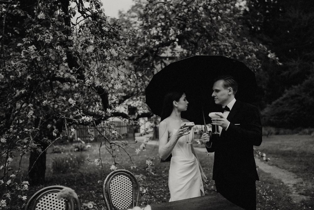 Black and white sequence of a couple enjoying champagne under umbrellas outdoors.