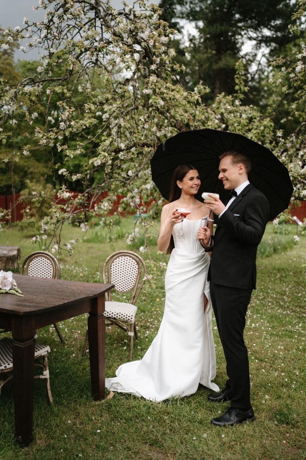 Wedding couple sharing intimate moments in a blooming spring garden with bistro furniture.