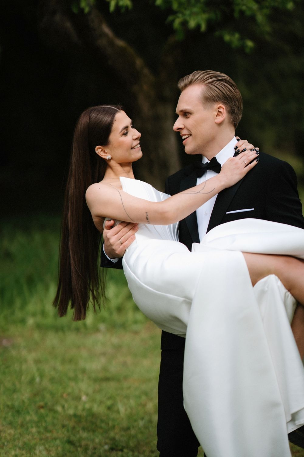 A tender embrace captured in an outdoor garden setting with elegant wedding attire.