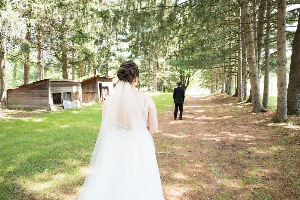 A couple in wedding attire walks through a serene wooded forest path during a romantic outdoor photo session.