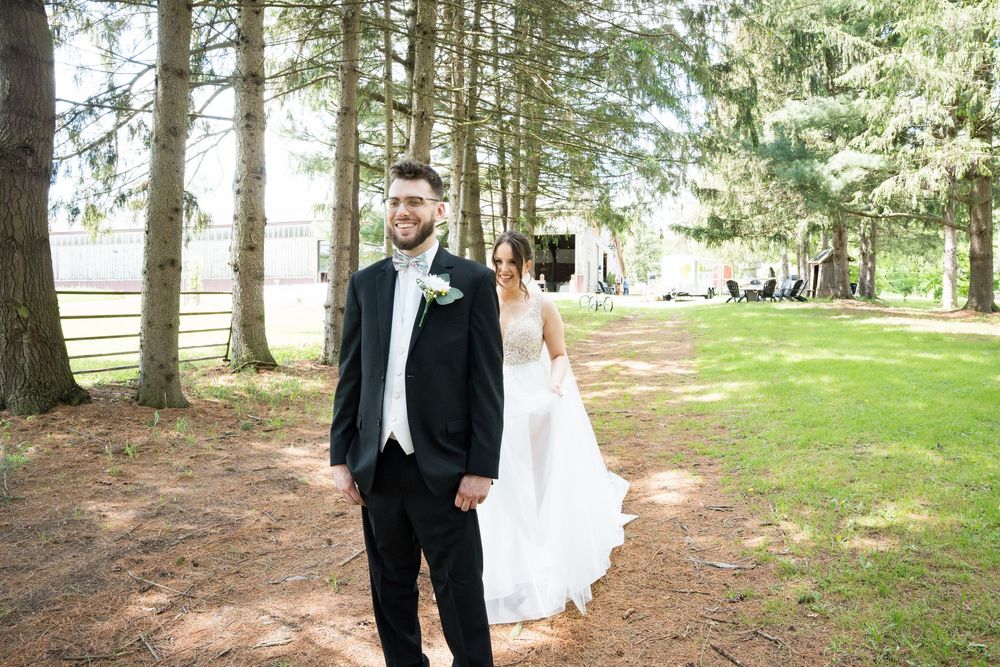 A couple shares a romantic first look moment in a sunlit pine forest setting on their wedding day.