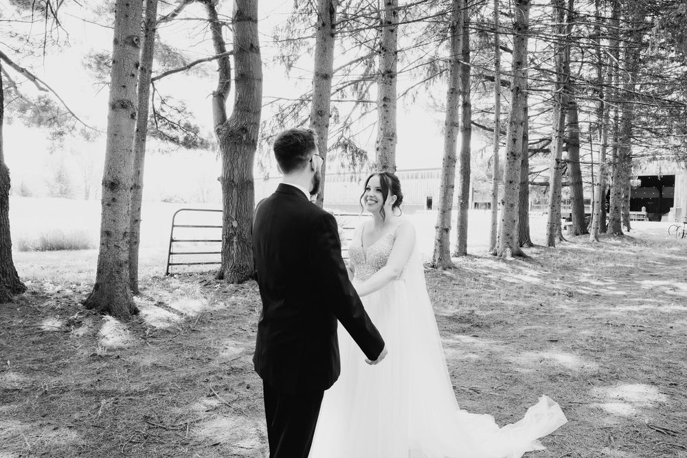 A romantic black and white photograph of a couple on their wedding day in a wooded forest setting.