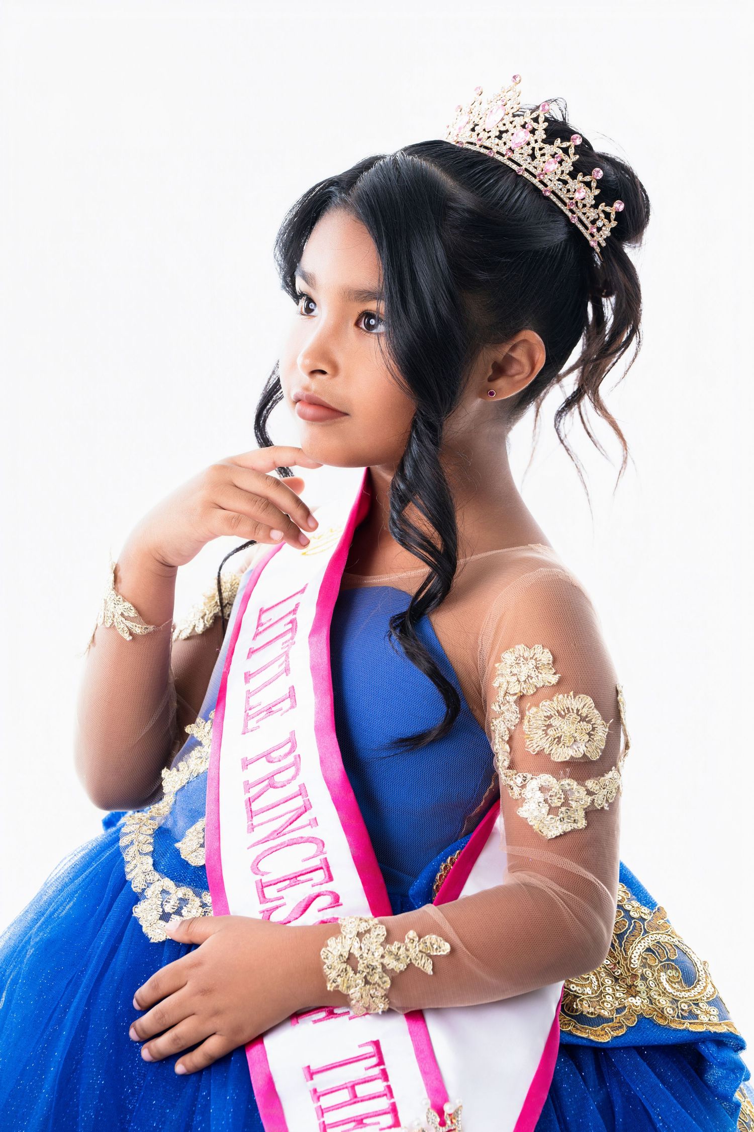 Pageant photo session featuring blue ball gown with gold accents and pink sash.