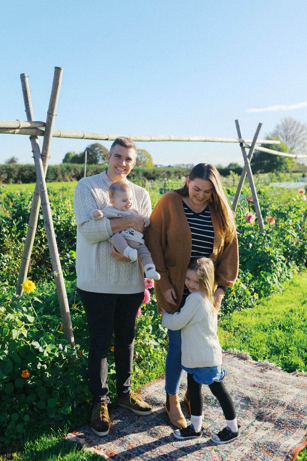 Couple spending time together at a sunny pumpkin patch with wooden posts marking the path through the field.