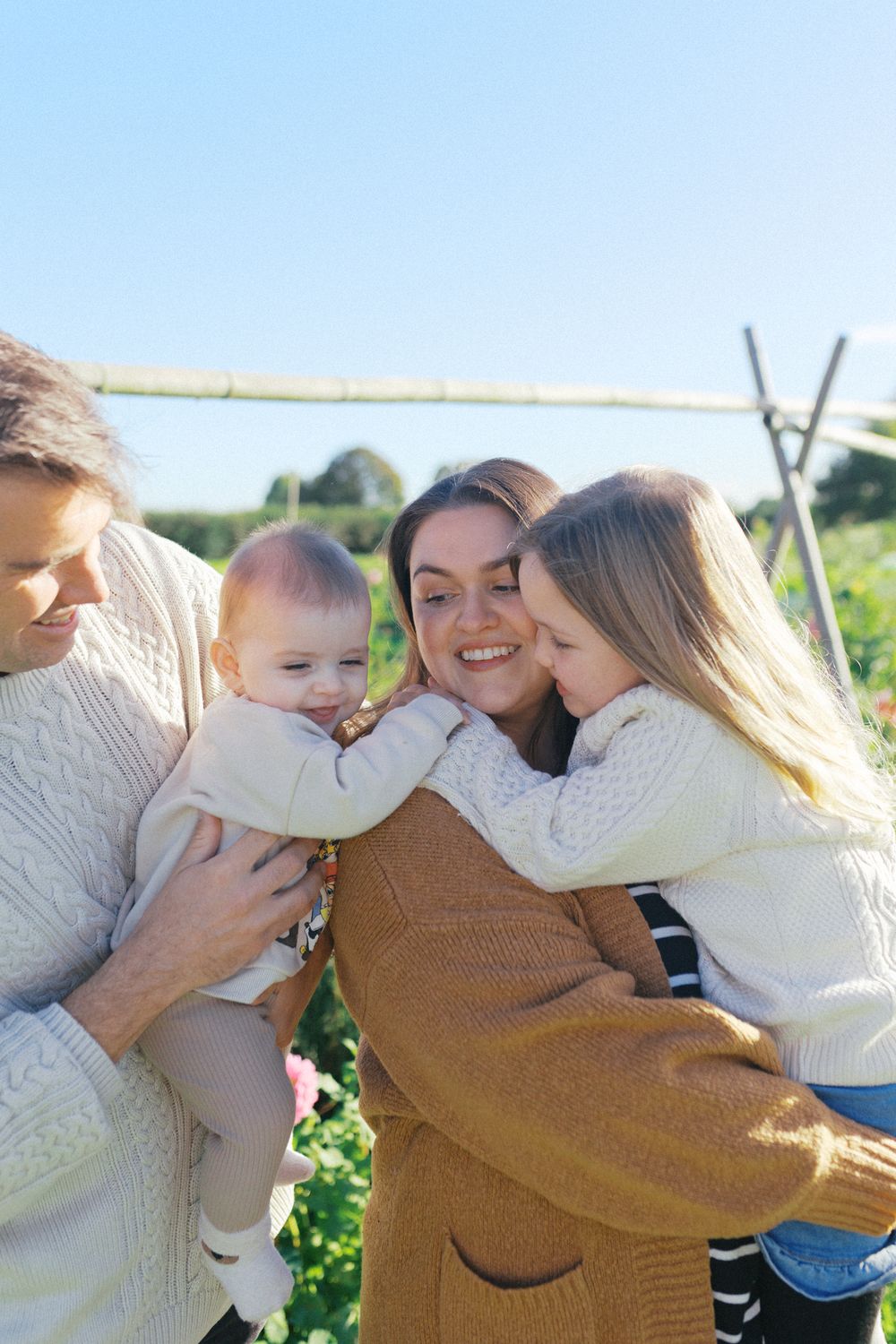 A loving family embraces each other outdoors on a sunny day, sharing warm hugs and tender moments.