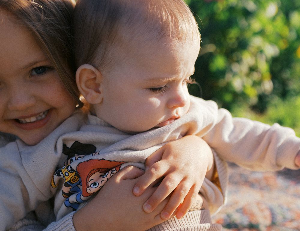 Affectionate parent lovingly touches child's cheek in sunlit outdoor scene.
