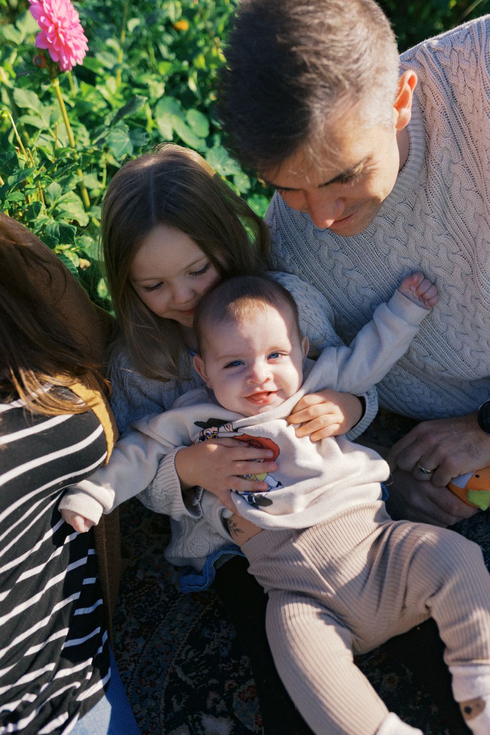 A sequence of tender parental moments captured outdoors with a baby in a light-colored sweater.