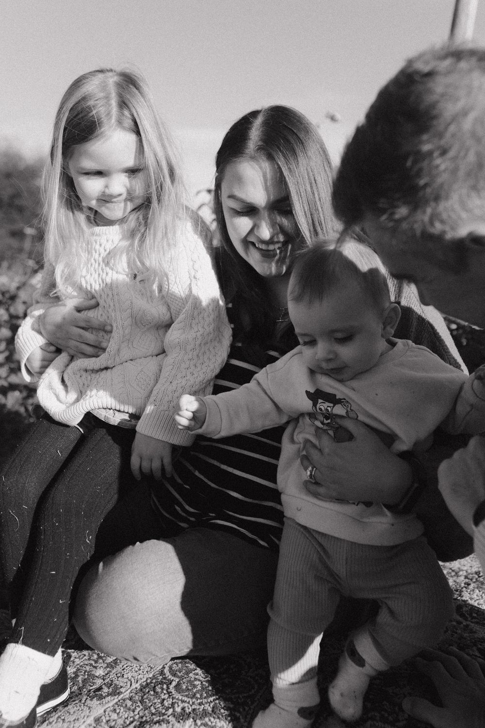 A heartwarming black and white photo of a family moment outdoors on a blanket.