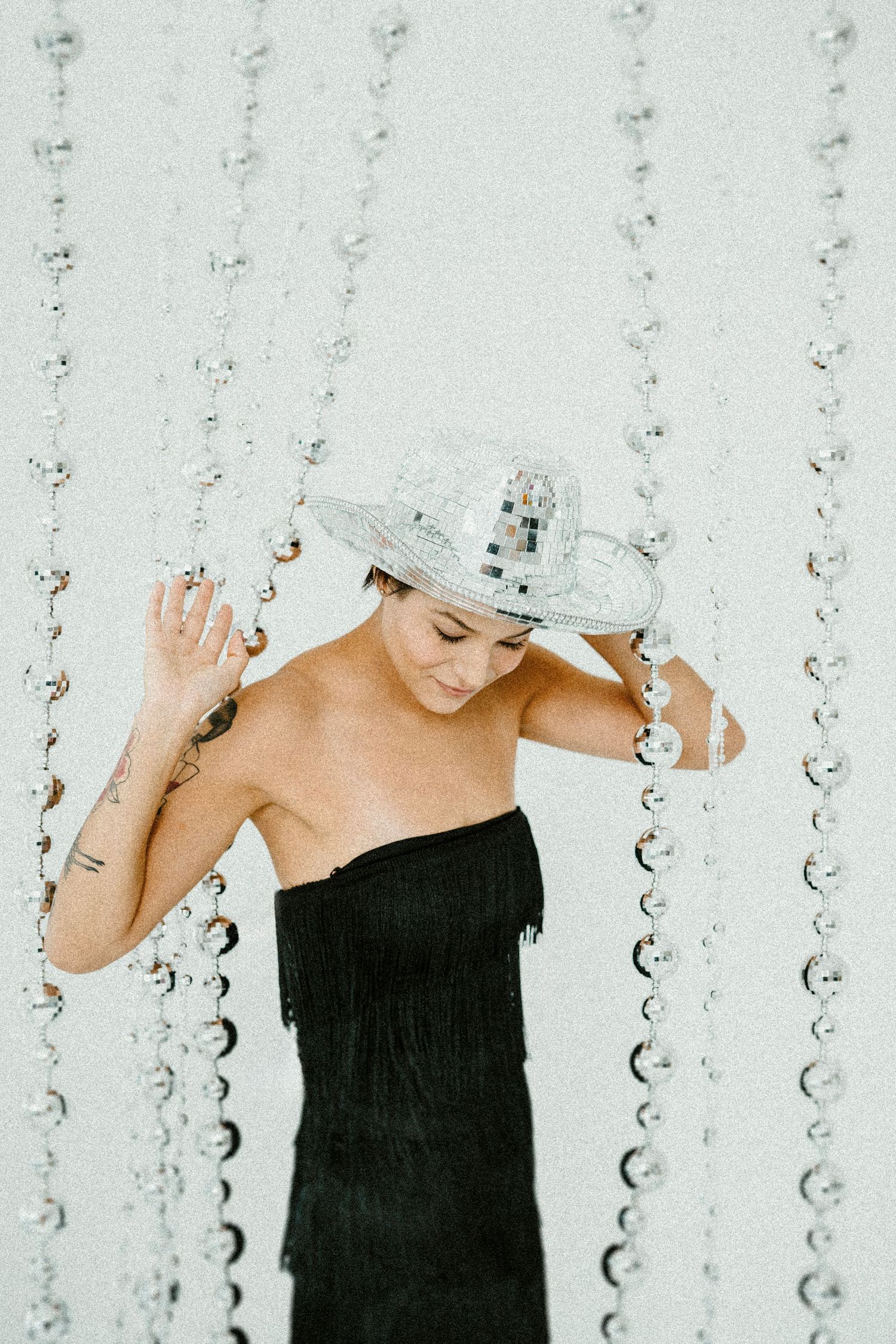 Dramatic black and white portrait with crystal garland decorations creating ethereal lighting effect.