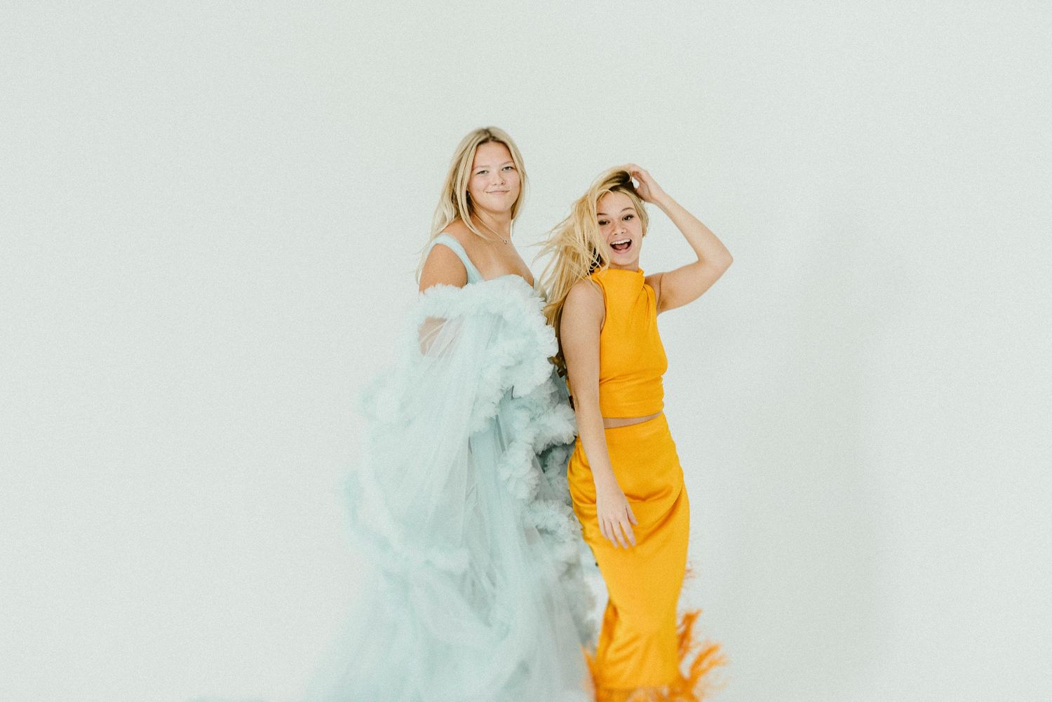 Person in bright yellow dress dances and poses against light blue background with flowing smoke effects.
