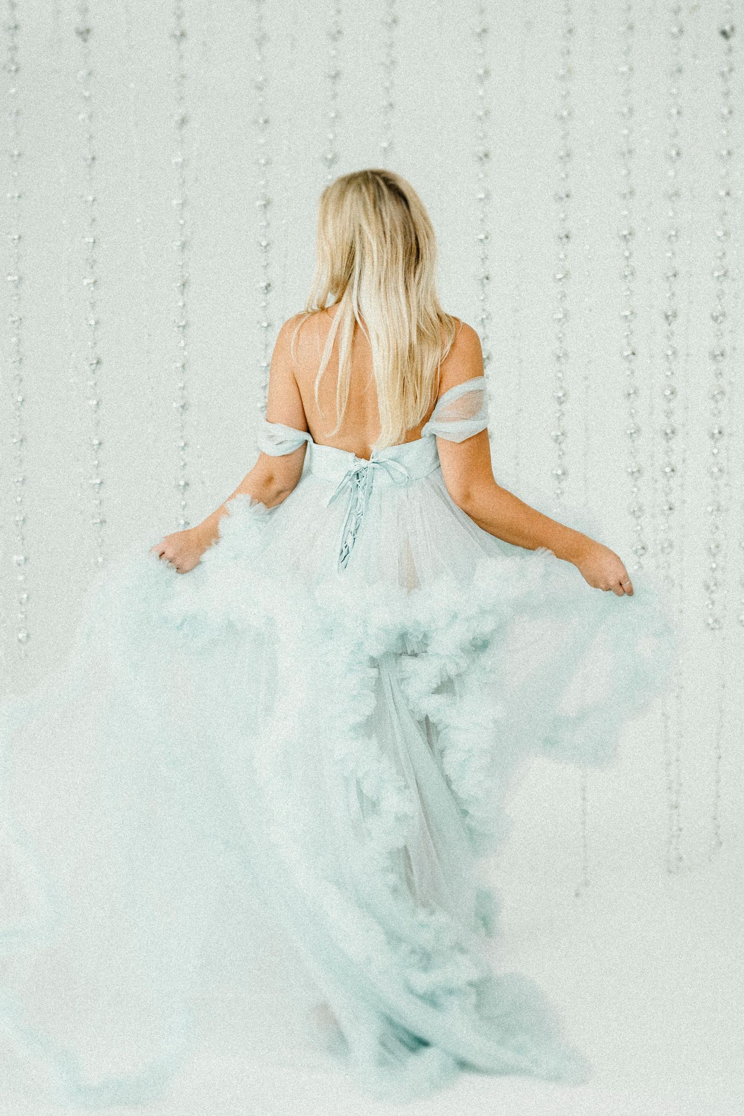 Ethereal sequence of a person in a flowing light blue gown twirling against a sparkling backdrop.