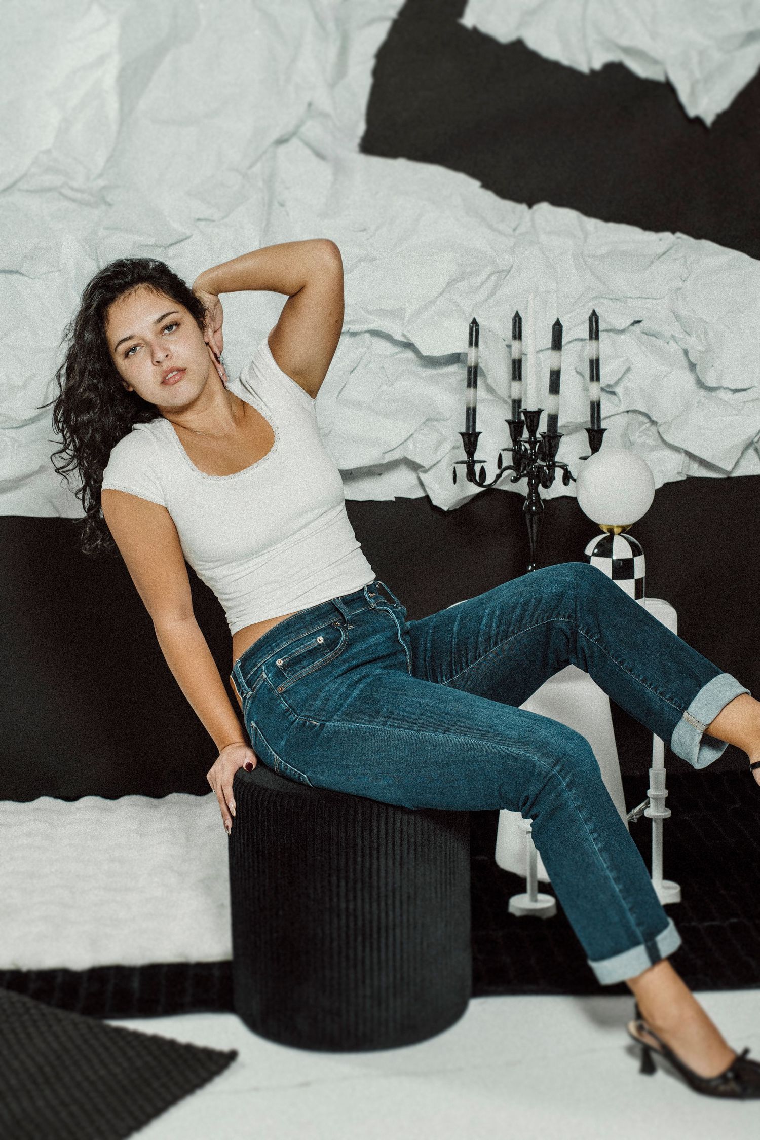 Stylish casual look with white t-shirt and blue jeans complemented by a decorative candelabra in studio setting.